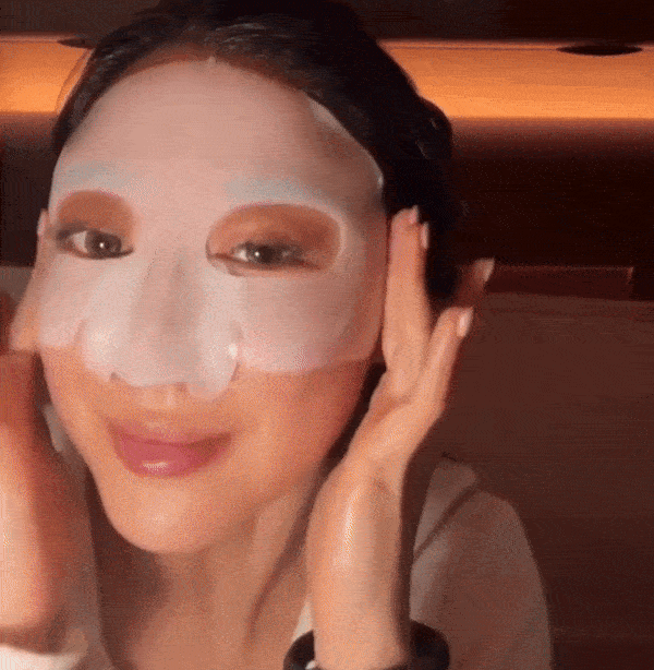 Kvinna med mörkt hår och bruna ögon applicerar först och drar sedan av en kollagenmask från ansiktet vilket visar en skinande och slät hud.